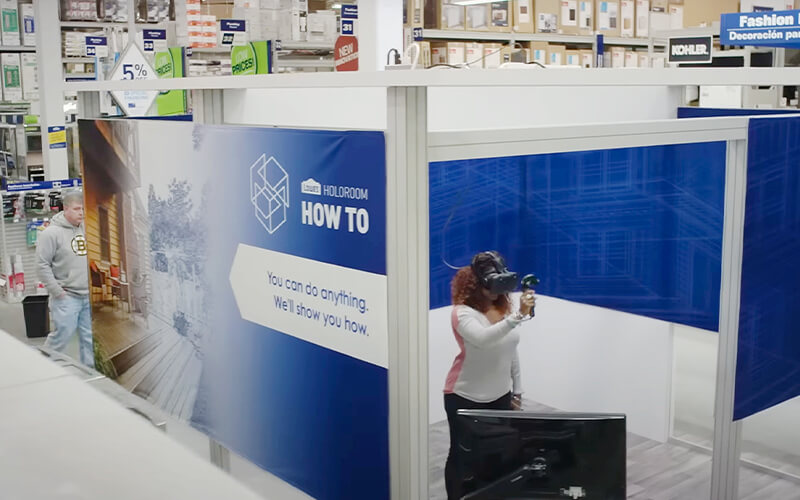 Lowe's Home Improvement holoroom experience with African-American female inside wearing VR headset learning DIY skills.