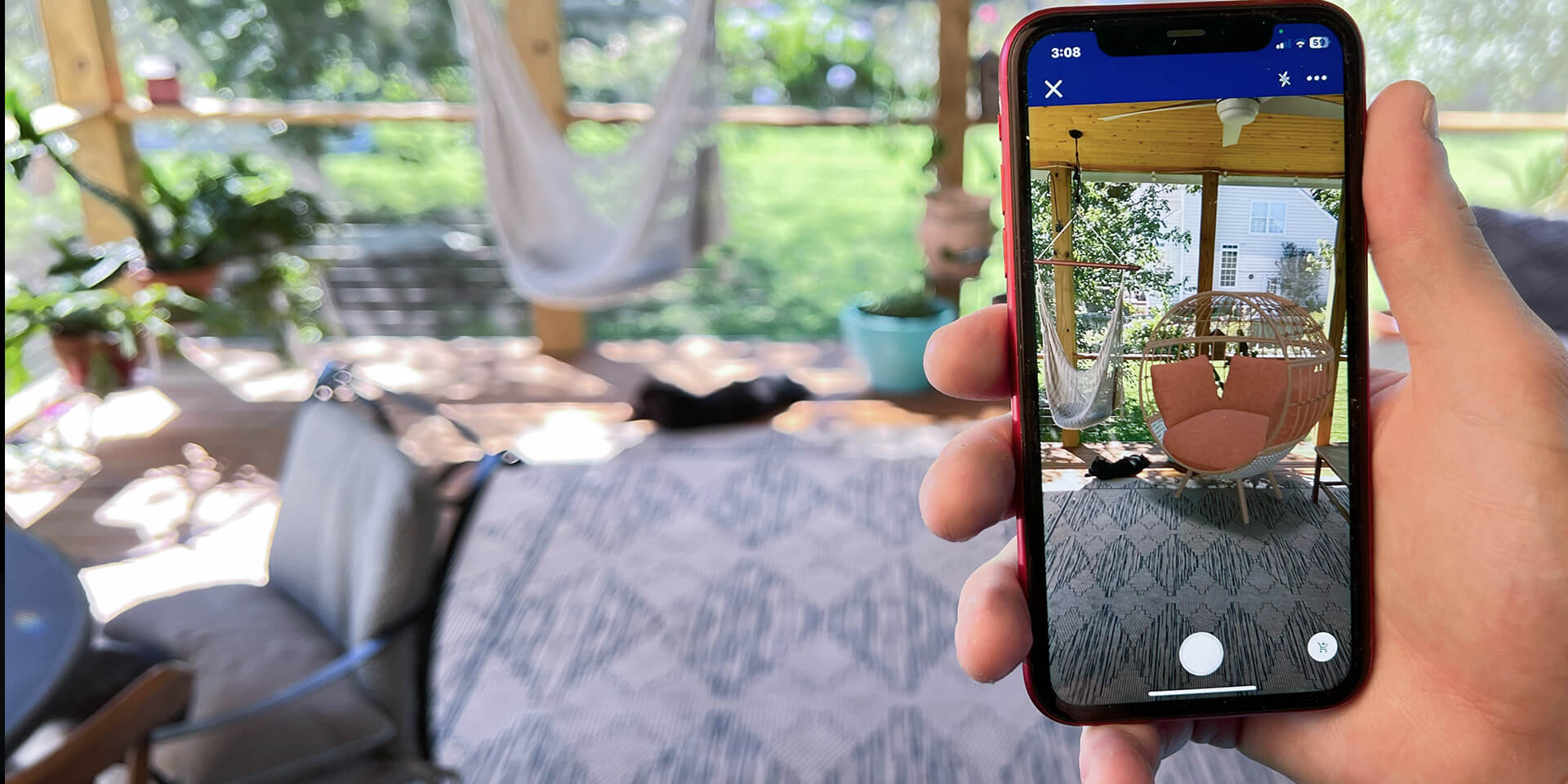 Person holding mobile phone looking at a virtual product in their outside living area through Lowe's Home Improvement AR visualizer. 
