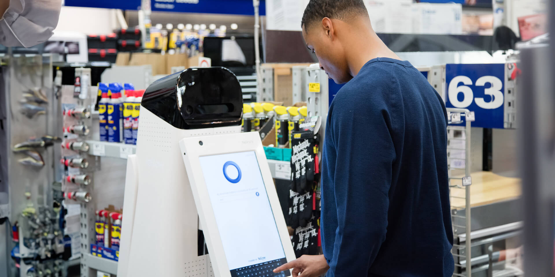 African-American male customer in a Lowe's Home Improvement store using the LoweBot to search for a product. 