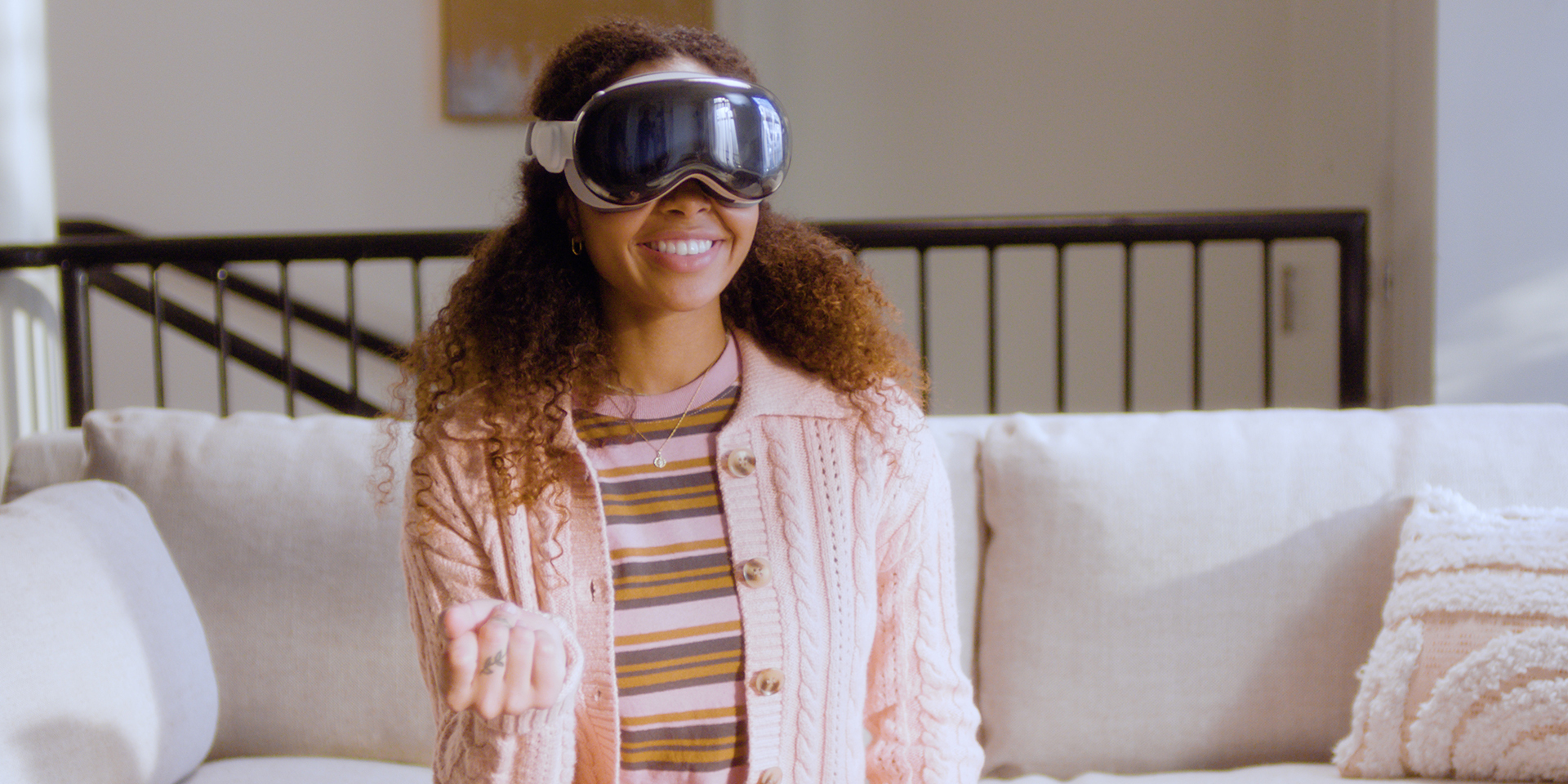 African-American woman sitting in her living room, wearing an Apple Vision Pro headset experiencing Lowe's Innovation Labs app 'Lowe's Style Studio.'